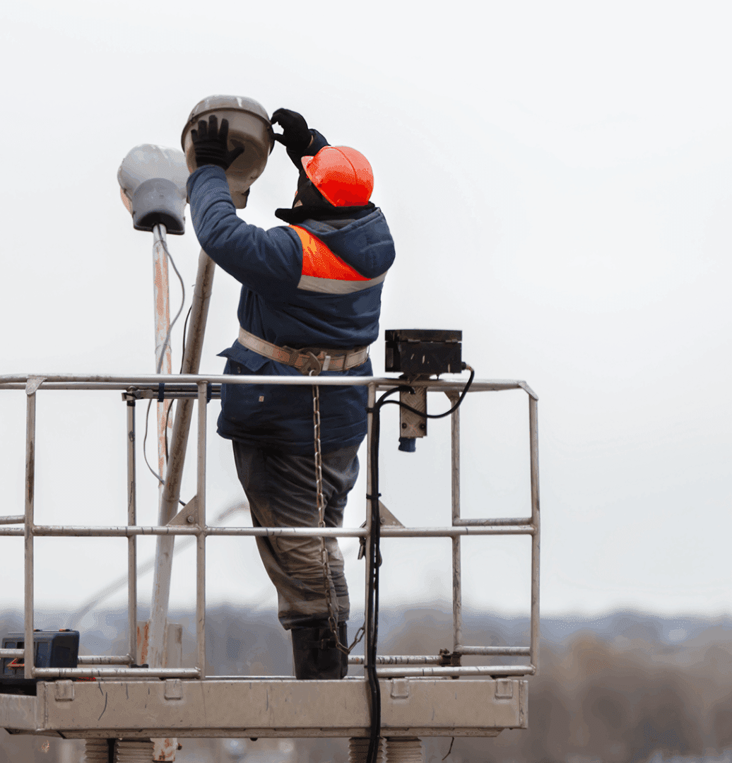 Worker installing streetlight on elevated platform.